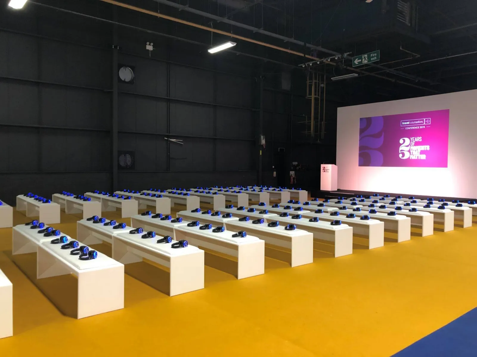 Auditorio de feria con bancos y auriculares preparados frente al escenario